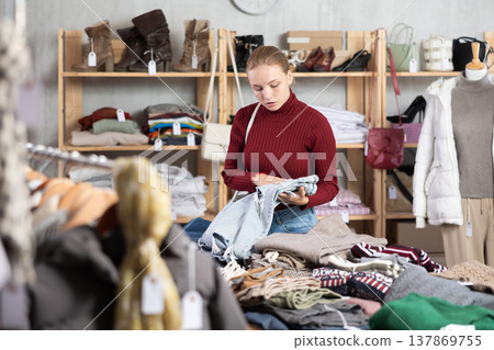 While shopping, teen girl browsing goods items and choose elect denim trousers in store While shopping, teen girl browsing goods items and choose elect denim trousers in store 137869755
