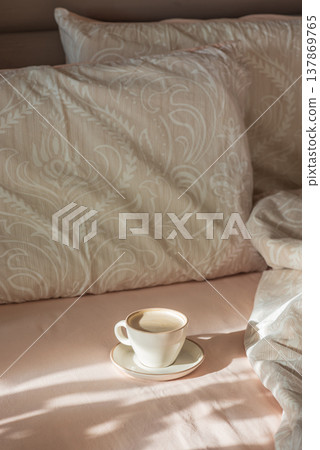Cappuccino Cup on Cozy Bed with Sunlight and Beige Bedding Cappuccino Cup on Cozy Bed with Sunlight and Beige Bedding 137869765