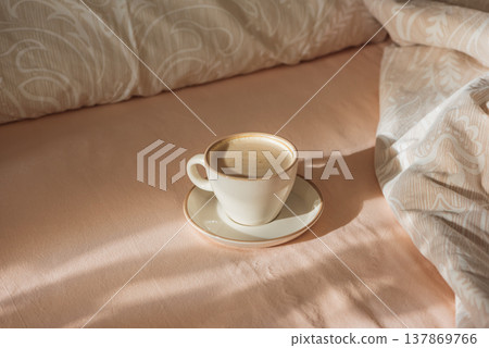Cappuccino Cup on Cozy Bed with Sunlight and Beige Bedding Cappuccino Cup on Cozy Bed with Sunlight and Beige Bedding 137869766