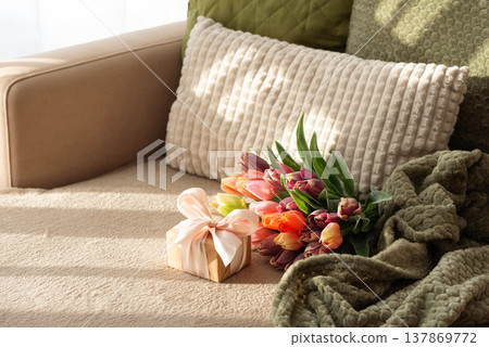 Tulip Bouquet and Gift Box on Cozy Sofa under Sunlight. Tulip Bouquet and Gift Box on Cozy Sofa under Sunlight. 137869772