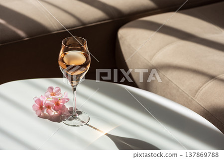 Rose Wine Glass with Shadows on White Table. Elegant Minimalist Scene Rose Wine Glass with Shadows on White Table. Elegant Minimalist Scene 137869788