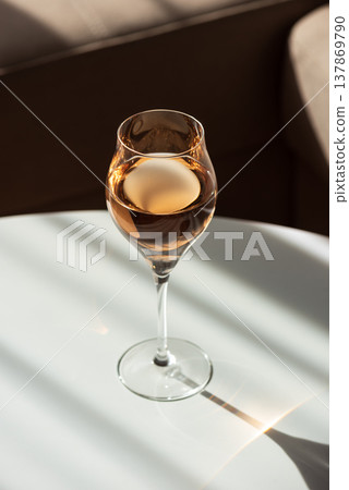 Rose Wine Glass with Shadows on White Table. Elegant Minimalist Scene Rose Wine Glass with Shadows on White Table. Elegant Minimalist Scene 137869790