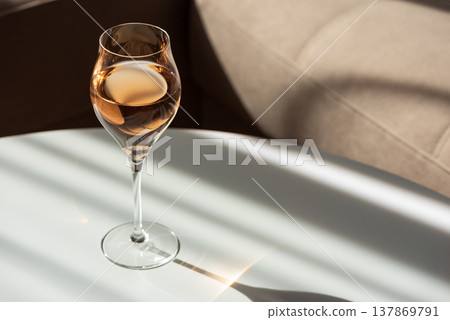 Rose Wine Glass with Shadows on White Table. Elegant Minimalist Scene Rose Wine Glass with Shadows on White Table. Elegant Minimalist Scene 137869791
