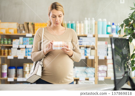 Pregnant woman chooses pills at pharmacy Pregnant woman chooses pills at pharmacy 137869818