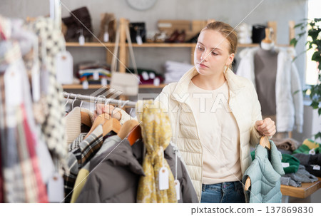 While shopping, teen girl browsing goods items and choose elect something warm outerwear in store While shopping, teen girl browsing goods items and choose elect something warm outerwear in store 137869830