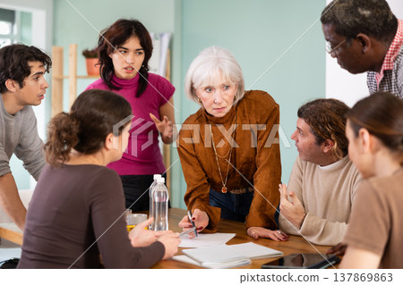 Men and women of different ages actively communicating at table 137869863