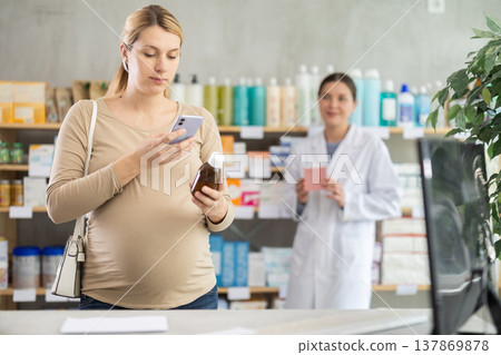 Pregnant woman scanning syrup bottle with phone to check ingredients online 137869878
