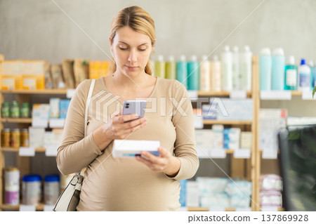 Pregnant woman customer scanning QR-code on ointment box 137869928