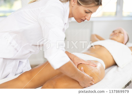 Close-up of young woman getting thigh massage Close-up of young woman getting thigh massage 137869979