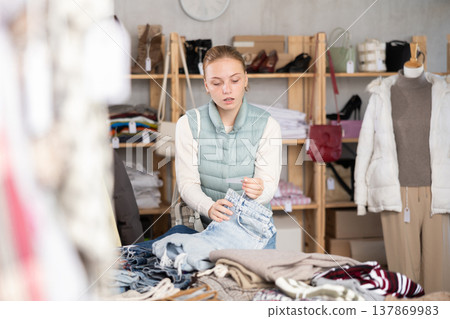 While shopping, teen girl browsing goods items and choose elect denim trousers in store While shopping, teen girl browsing goods items and choose elect denim trousers in store 137869983