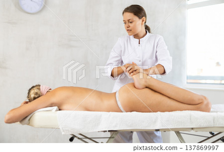 Young woman masseuse doing foot massage 137869997