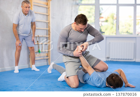 Adult and young men training self-defense techniques 137870016