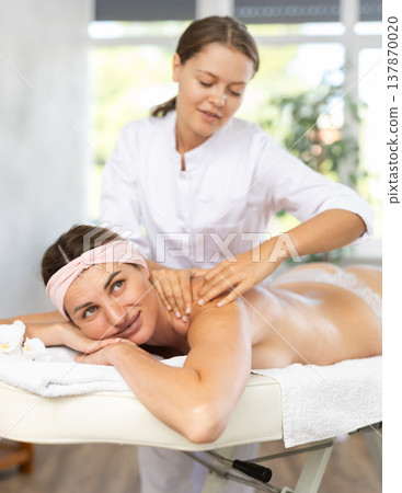 Adult woman gets back and shoulder massage 137870020