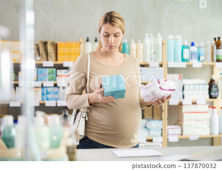 Pregnant woman in drugstore chooses woman pads Pregnant woman in drugstore chooses woman pads 137870032