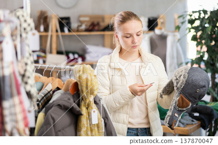 While shopping, teen girl browsing goods items and choose elect fur hat in store 137870047