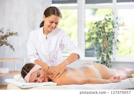 Young woman masseuse doing back massage 137870057