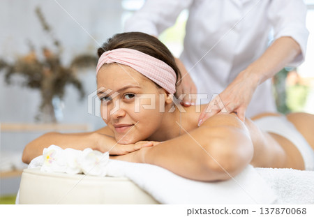 Female masseur works out shoulder and back problem area for female athlete client. Close-up 137870068