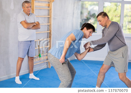 Two athlete men of different age in sportswear practicing self-defense sparring in hall Two athlete men of different age in sportswear practicing self-defense sparring in hall 137870070