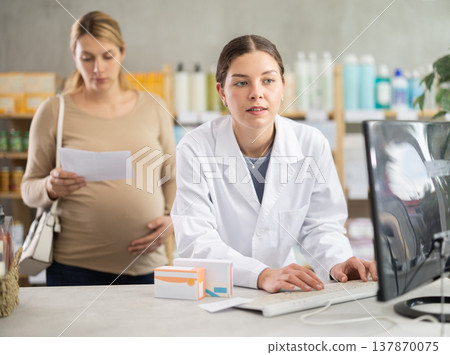 Pharmacist checking supplements safety for expecting woman with prescription Pharmacist checking supplements safety for expecting woman with prescription 137870075