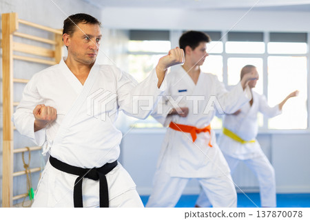 Man in white kimono performing kata routines at martial arts training Man in white kimono performing kata routines at martial arts training 137870078