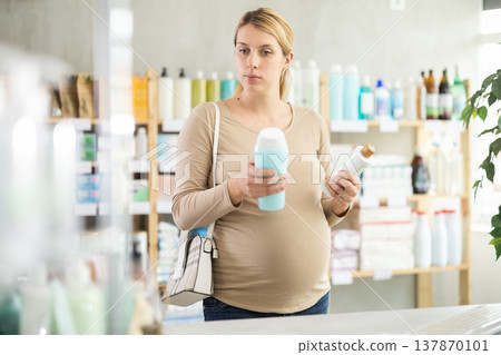 Pregnant woman choose antidandruff shampoo in pharmacy Pregnant woman choose antidandruff shampoo in pharmacy 137870101