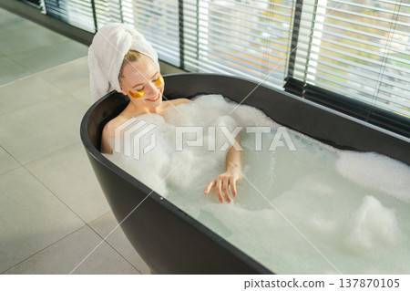 Spa relaxation. Young woman lying in bath with foam bubbles. Girl relaxing in bathroom at home. Pretty female spending morning in bathroom enjoying taking bath. Beauty treatment body skin care concept Spa relaxation. Young woman lying in bath with foam bubbles. Girl relaxing in bathroom at home. Pretty female spending morning in bathroom enjoying taking bath. Beauty treatment body skin care concept 137870105
