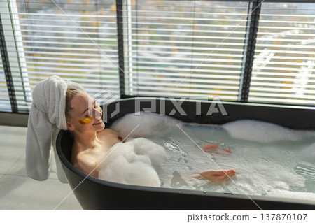 Spa relaxation. Young woman lying in bath with foam bubbles. Girl relaxing in bathroom at home. Pretty female spending morning in bathroom enjoying taking bath. Beauty treatment body skin care concept 137870107