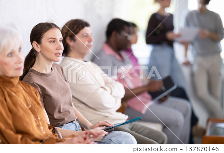 Man and a woman chat while waiting for their turn at job interview in an office Man and a woman chat while waiting for their turn at job interview in an office 137870146