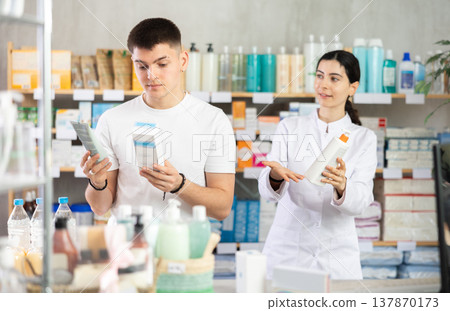 Guy buys emollient cream at pharmacy. Pharmacist offer help and similar product Guy buys emollient cream at pharmacy. Pharmacist offer help and similar product 137870173