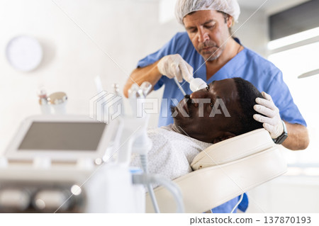 African American undergoing cosmetic facial treatment using cold hammer African American undergoing cosmetic facial treatment using cold hammer 137870193