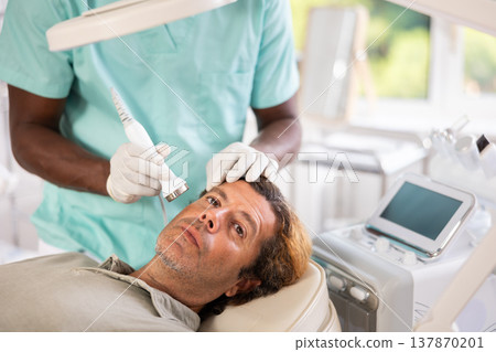 Adult man undergoing high frequency ultrasound facial treatment Adult man undergoing high frequency ultrasound facial treatment 137870201