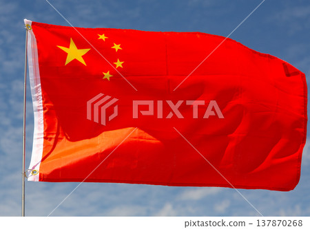Flag of China waving on flagpole against blue sky on sunny day 137870268