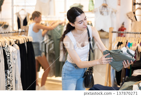 Young woman choosing green pants in store 137870271