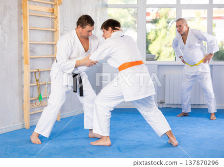 Experienced karate instructor demonstrating techniques in sparring with young fighter Experienced karate instructor demonstrating techniques in sparring with young fighter 137870296
