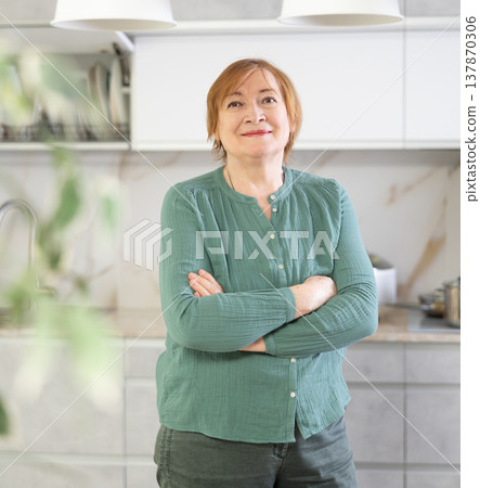 Portrait of a smiling mature woman in the kitchen Portrait of a smiling mature woman in the kitchen 137870306
