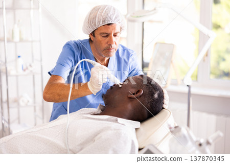 Doctor uses RF-lifting beauty machine nozzle for stimulate collagen production 137870345