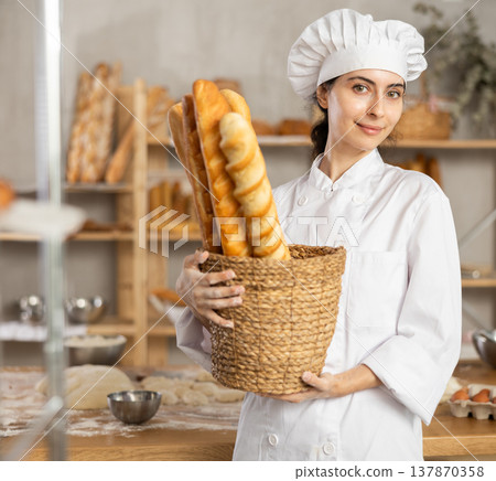 Young female baker with basket of baguettes 137870358