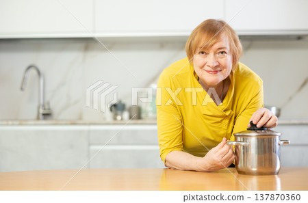 Portrait of a smiling mature woman in the kitchen near the table 137870360