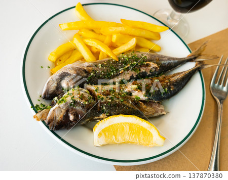 Grilled mackerels with French fries, lemon and sauce 137870380