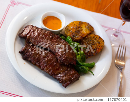 Grilled veal steaks served with baked potatoes, jalapeno and chimichurri Grilled veal steaks served with baked potatoes, jalapeno and chimichurri 137870401
