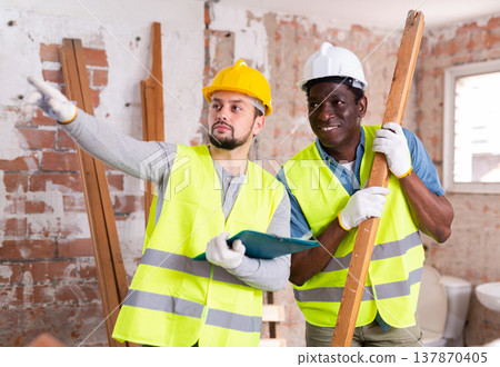 Two builders talking on indoor construction site Two builders talking on indoor construction site 137870405