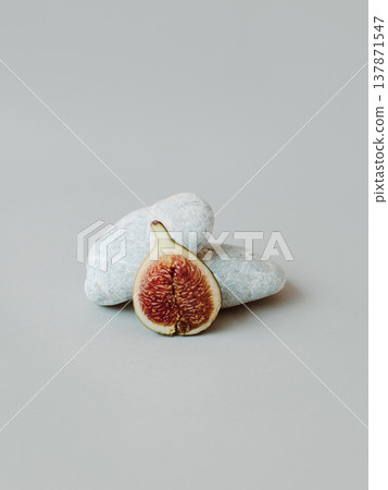 Ripe fig with stones on a grey background. Minimal concept. Ripe fig with stones on a grey background. Minimal concept. 137871547