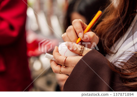 Hands Sketching Egg. Artist Sketching Vibrant Red Line On Egg Shell In Openair Workshop Setting 137871894