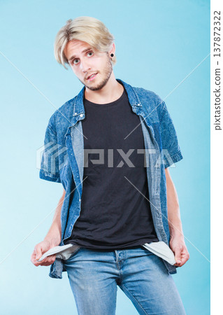 Upset sad man showing empty pockets Upset sad man showing empty pockets 137872322