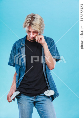 Upset sad man showing empty pockets Upset sad man showing empty pockets 137872323