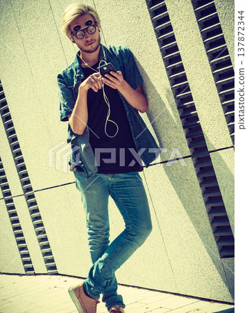 Hipster man listening music through earphones Hipster man listening music through earphones 137872344