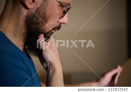 Bearded Man With Glasses Reading On Tablet, Deep In Thought, Profile Portrait Of Concentration Bearded Man With Glasses Reading On Tablet, Deep In Thought, Profile Portrait Of Concentration 137872597