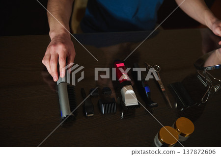 Barber Tools and Hair Clippers Laid Out on Dark Table With Hand Reaching Over Grooming Kit Barber Tools and Hair Clippers Laid Out on Dark Table With Hand Reaching Over Grooming Kit 137872606