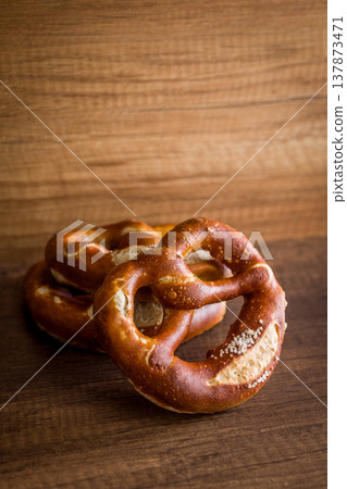 Soft Salted Pretzel on Rustic Wooden Table With Bakery Cloth. Close-Up Food Photography Soft Salted Pretzel on Rustic Wooden Table With Bakery Cloth. Close-Up Food Photography 137873471