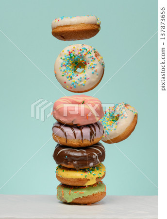 Stack of donuts with various fillings and glazes, several levitating upwards. 137873656